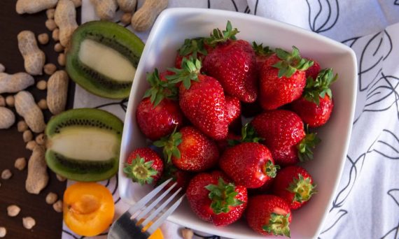 A vibrant flat lay of fresh strawberries and kiwi slices in a ceramic bowl, perfect for food photography.